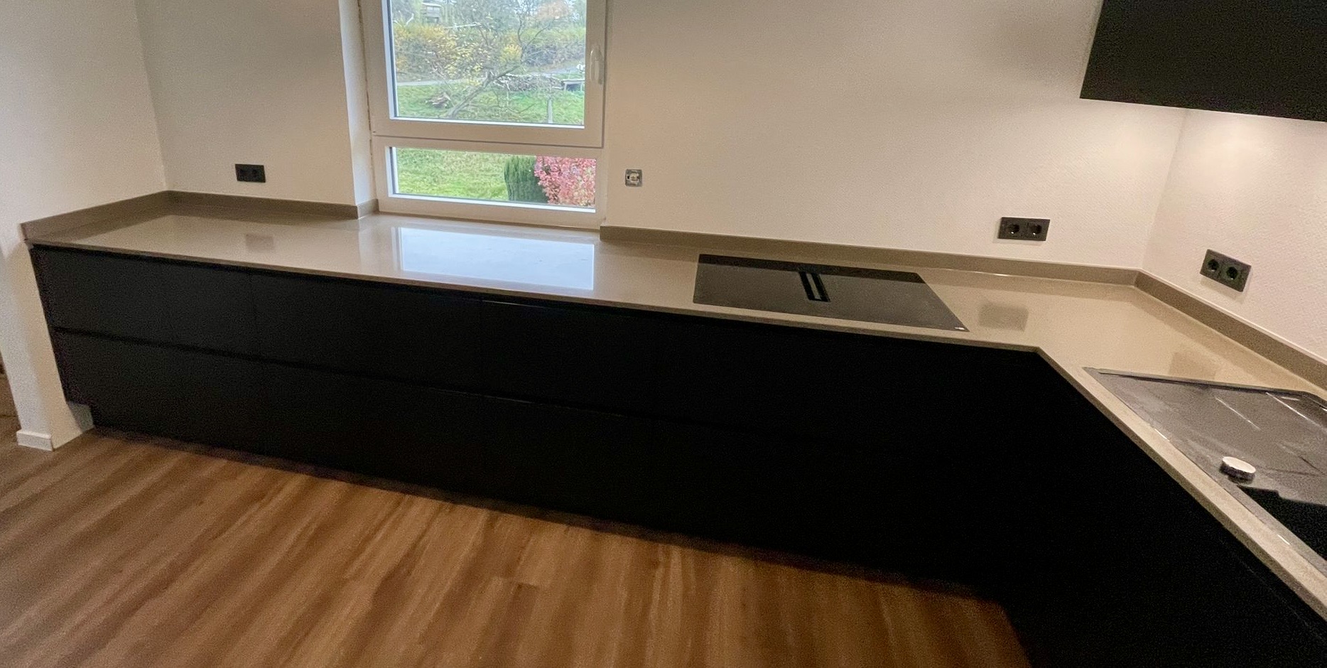 Referenzküche in schwarz mit Arbeitsplatte in Holzoptik. 